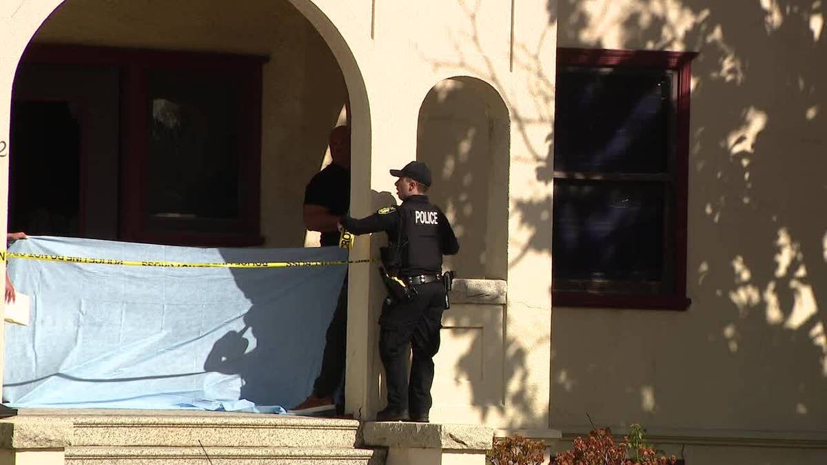 A Vallejo police officer stands behind yellow police tape in front of a home where a suspected burglar was shot and killed 